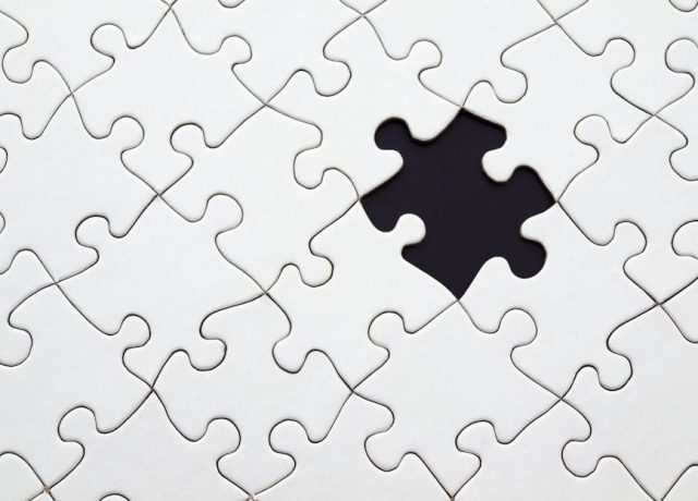 Close-up of an incomplete white puzzle with one missing piece, symbolizing challenge and strategy.